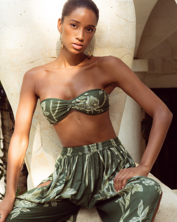 Woman in olive green floral strapless top and matching pants, exuding confidence and grace.