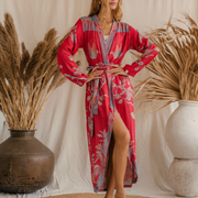 Woman in red floral kimono robe with high slit, standing on jute rug beside dried pampas grass in boho chic setting